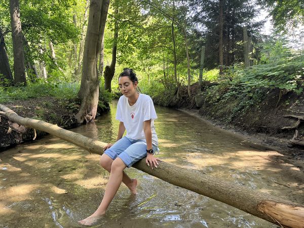 Entspannen am Werderfließ in Buckow Frau sitzt auf einem Baumstamm und hält die Füße ins Wasser