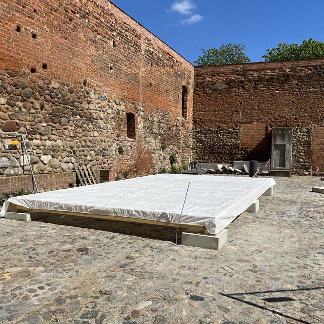 alte Mauern und davor Boden der neuen Burghofbühne