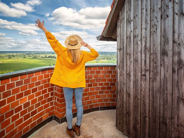 Eine Frau steht auf dem Bismarckturm in Bad Freienwalde und genießt die Aussicht auf die Weite des Oderbruchs