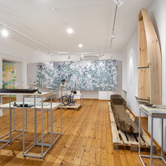 großer Ausstellungsraum mit Karte an der Wand und Boten an Wand und auf dem Boden
