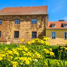 altes Gebäude und davor gelbe Blumen